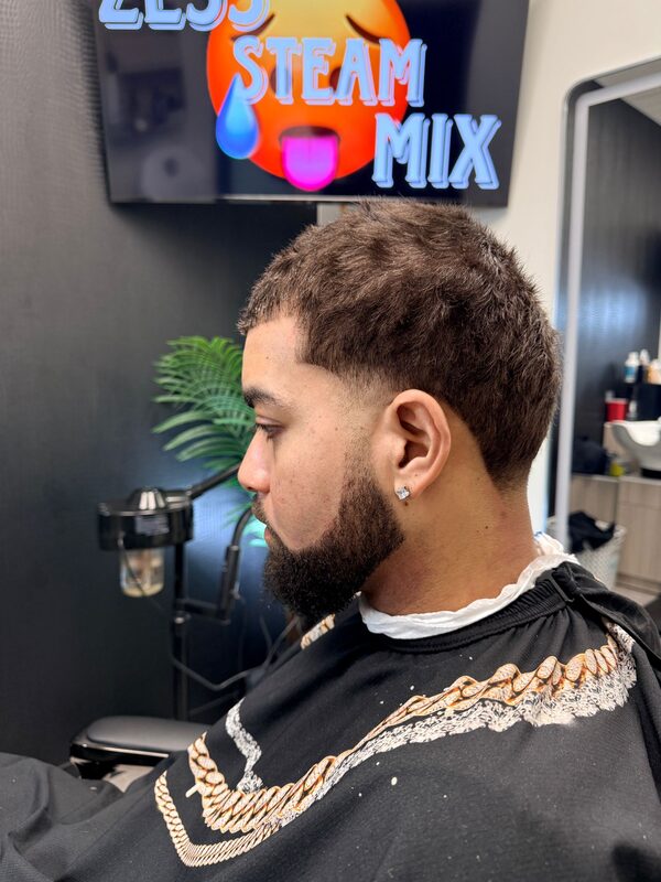 Side profile of a short textured crop with a low fade and a full trimmed beard