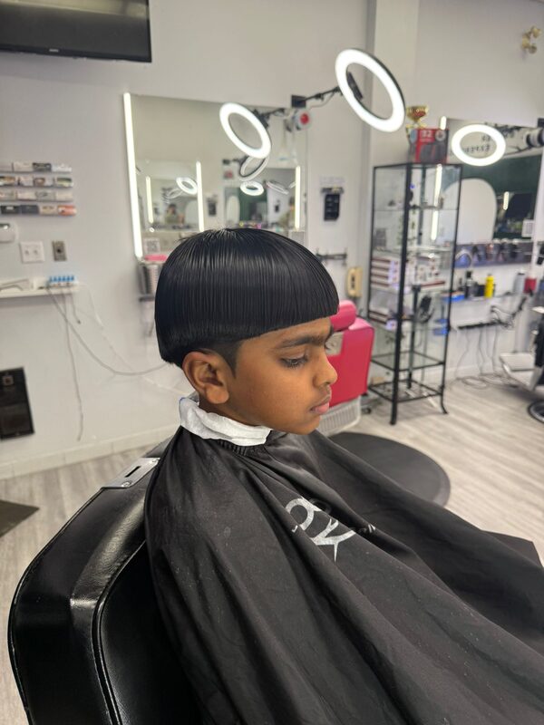 Side profile of a sleek, blunt-bang mushroom haircut on a child