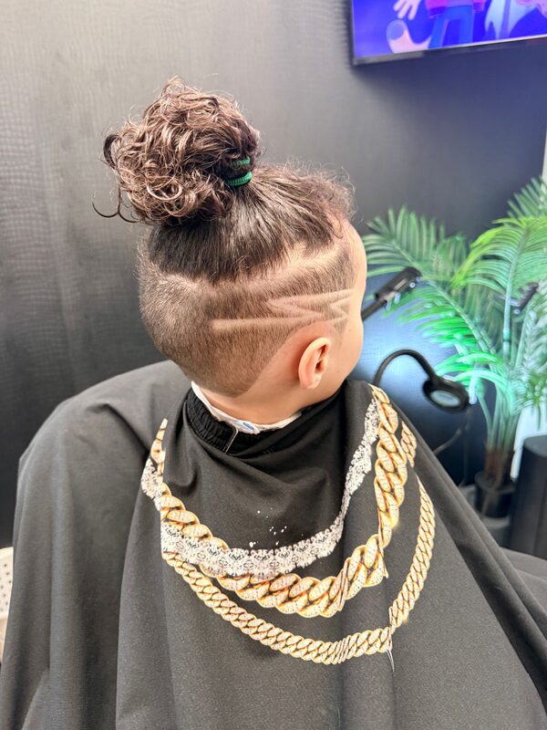 Back of the head showing a curly top knot with a zigzag hair-tattoo design shaved into the sides