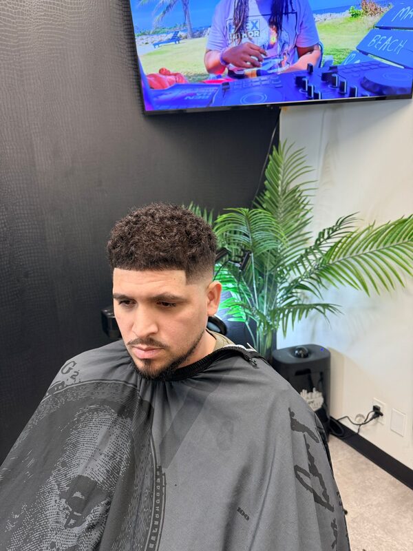 Side profile of a curly-top fade with a light beard