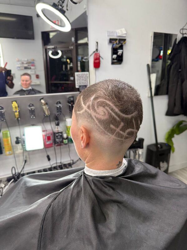 Back of the head showing a buzz cut with an intricate scroll hair-tattoo design