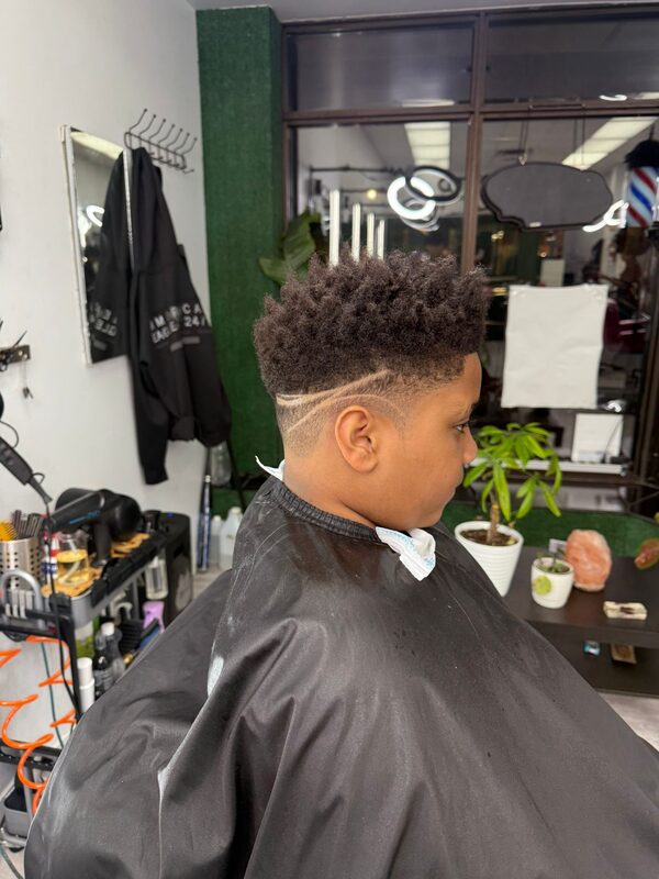 Side view of a curly textured top with a fade and a single line design shaved into the side