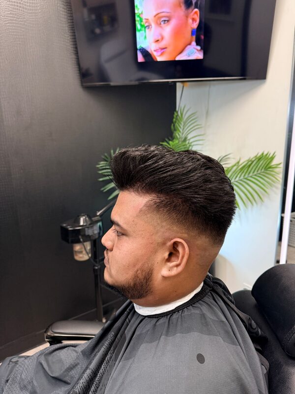 Side profile of a brushed-up pompadour with a mid fade and full beard