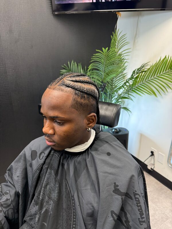 Side view of cornrow braids styled to one side over a low fade