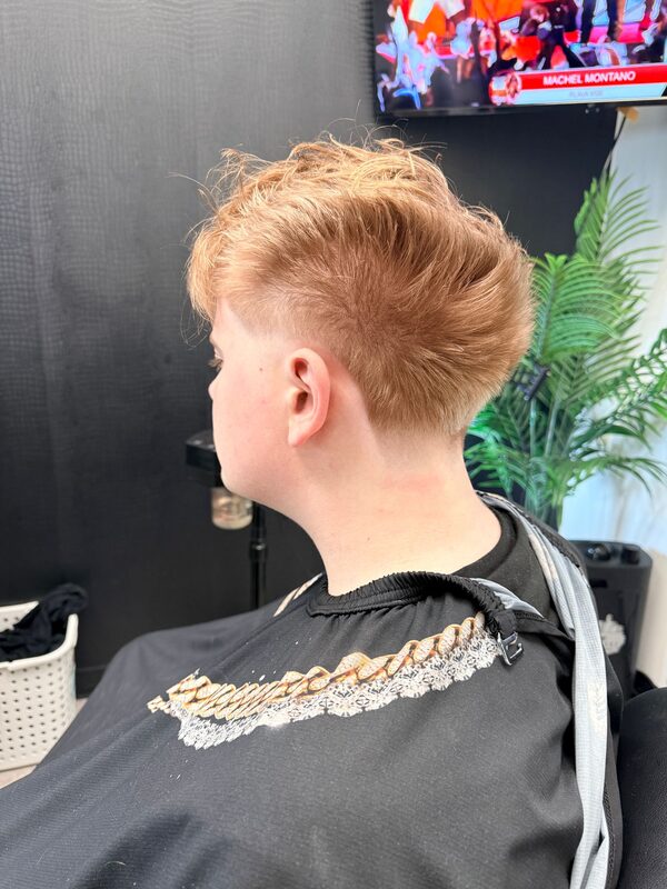 Back view of a wavy textured crop with a taper fade on strawberry-blond hair
