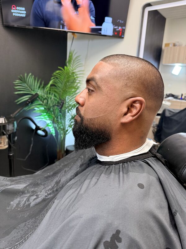 Side view of a close buzz cut with a sharply lined full beard