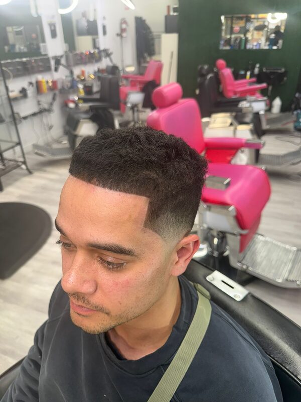 Side profile of a curly-top fade with a sharp hard-part line