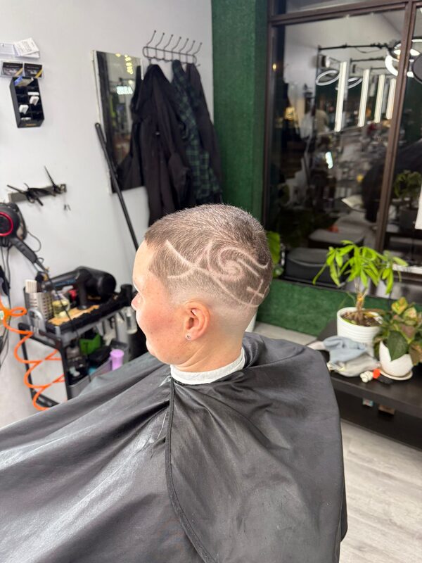 Back of the head showing a buzz cut with a swirling wave design shaved into the side