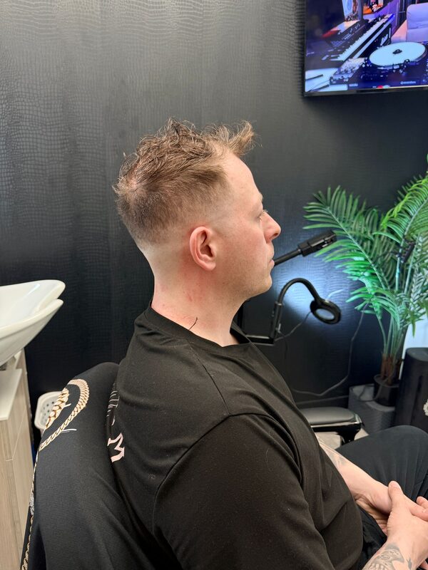Side profile of a short spiky textured crop with a low fade on blond hair