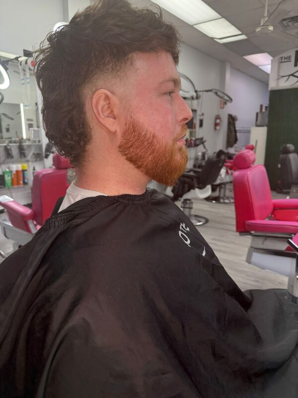 Side profile of a curly mullet with a fade and a full ginger beard